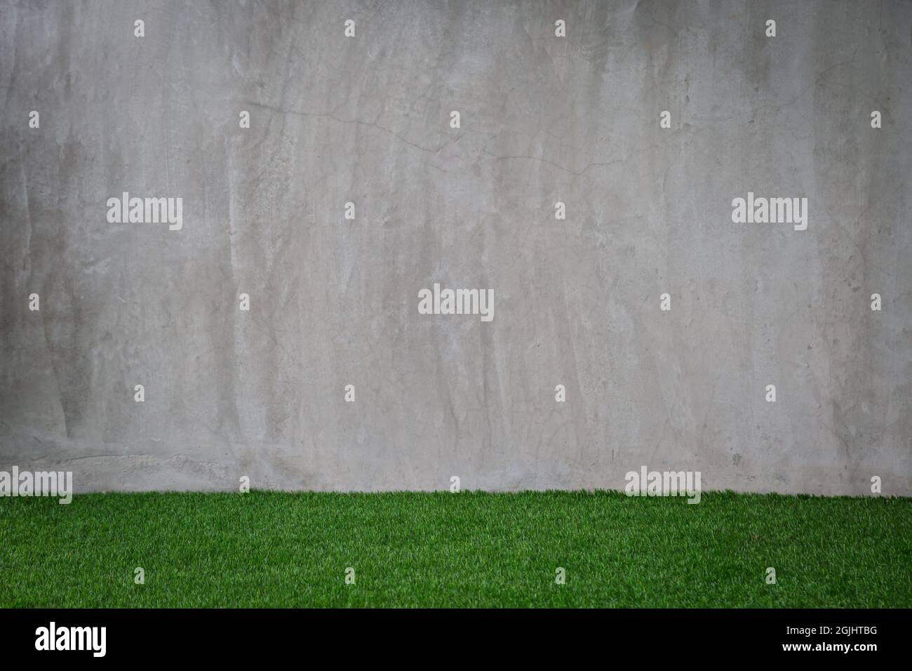 Motif gazon artificiel vert avec fond de mur en ciment gris Banque D'Images