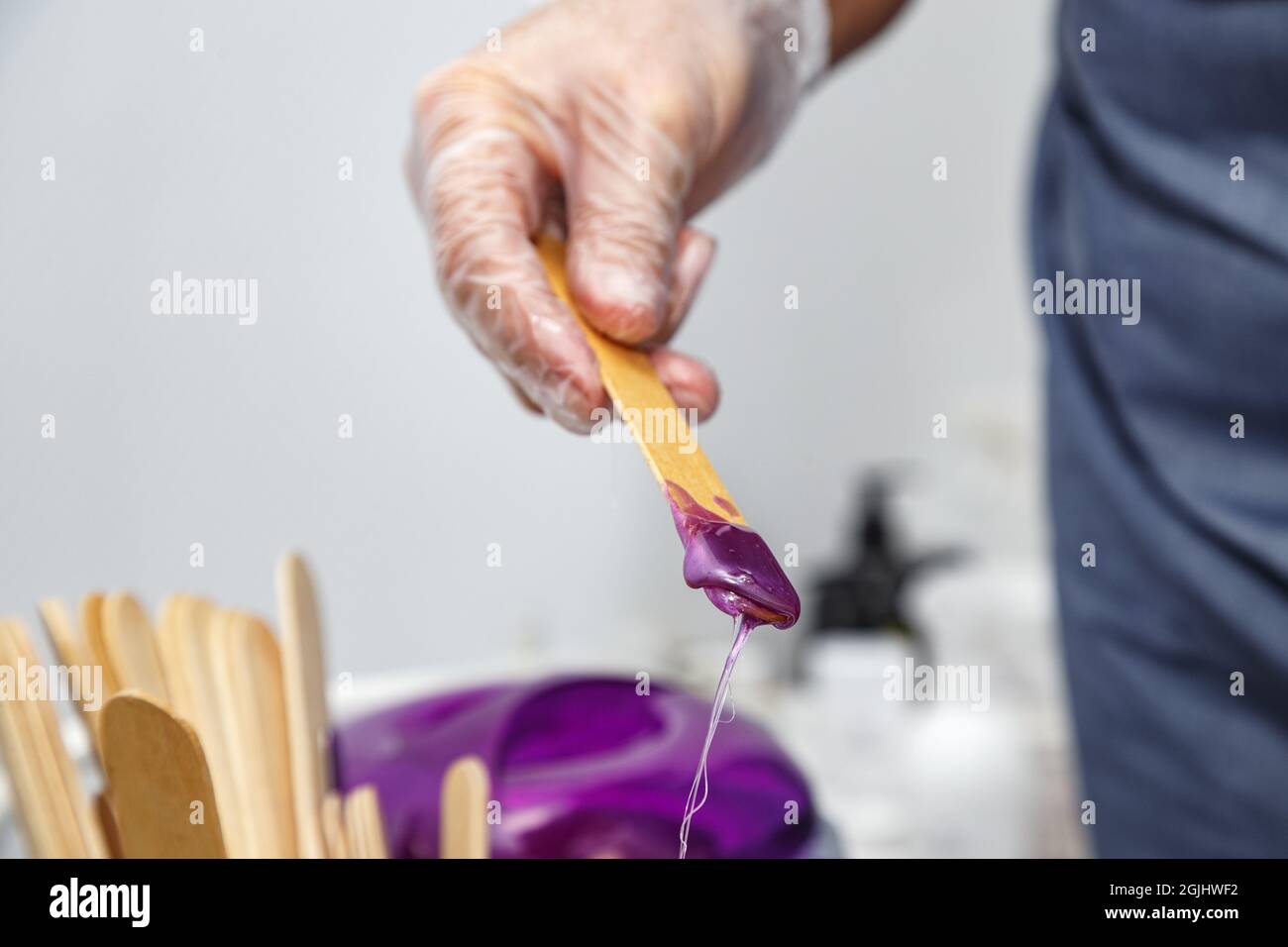 Cire violette fondue sur bâton de bois pour l'épilation Banque D'Images