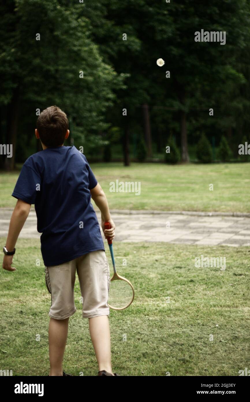 Jeune garçon jouant au badminton extérieur vue arrière photo d'un garçon jouant au badminton dans le parc Boy joue au badminton et balançoires balançoire de badminton Banque D'Images