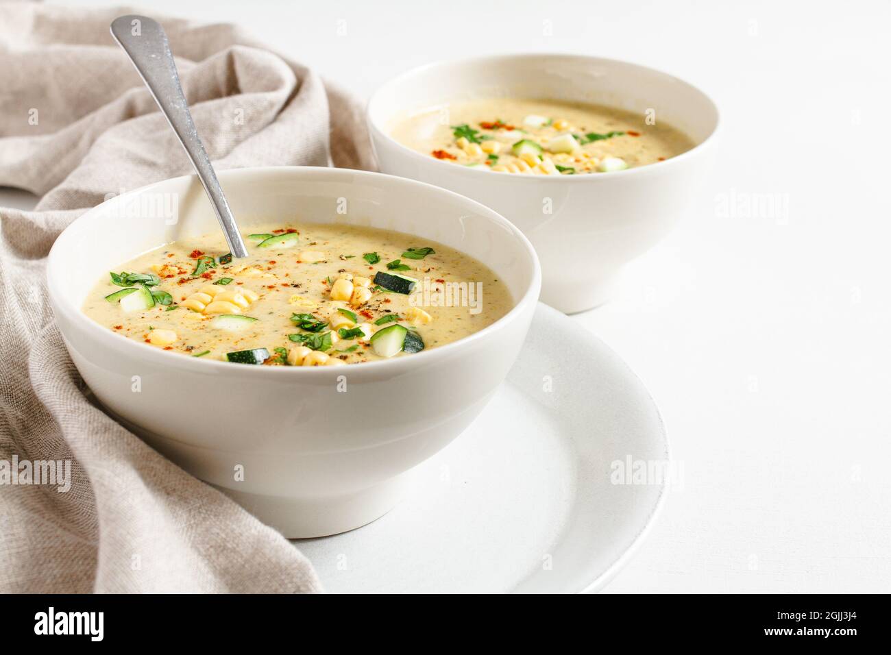 Deux bols de maïs crémeux et de courgette avec une cuillère à soupe dans un bol. Banque D'Images