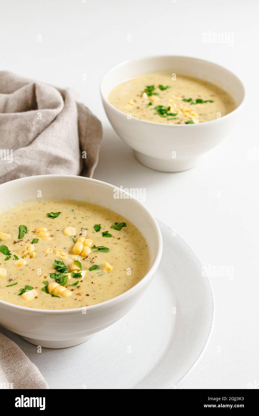 Deux bols de chaudrée de maïs maison surmontés de persil frais et de grains de maïs. Banque D'Images