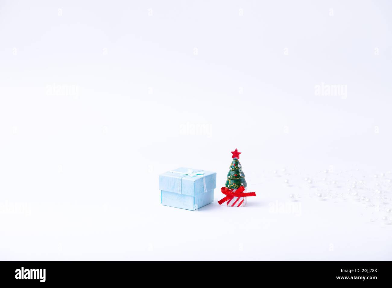 Sapin de Noël miniature, boîte cadeau et perles sur fond blanc. Nouvel an et Noël. Gros plan, bannière. Banque D'Images