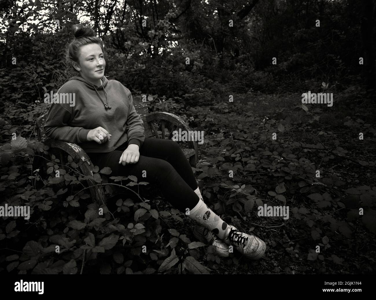 Jeune fille d'âge se reposant sur un bebch dans les bois Banque D'Images