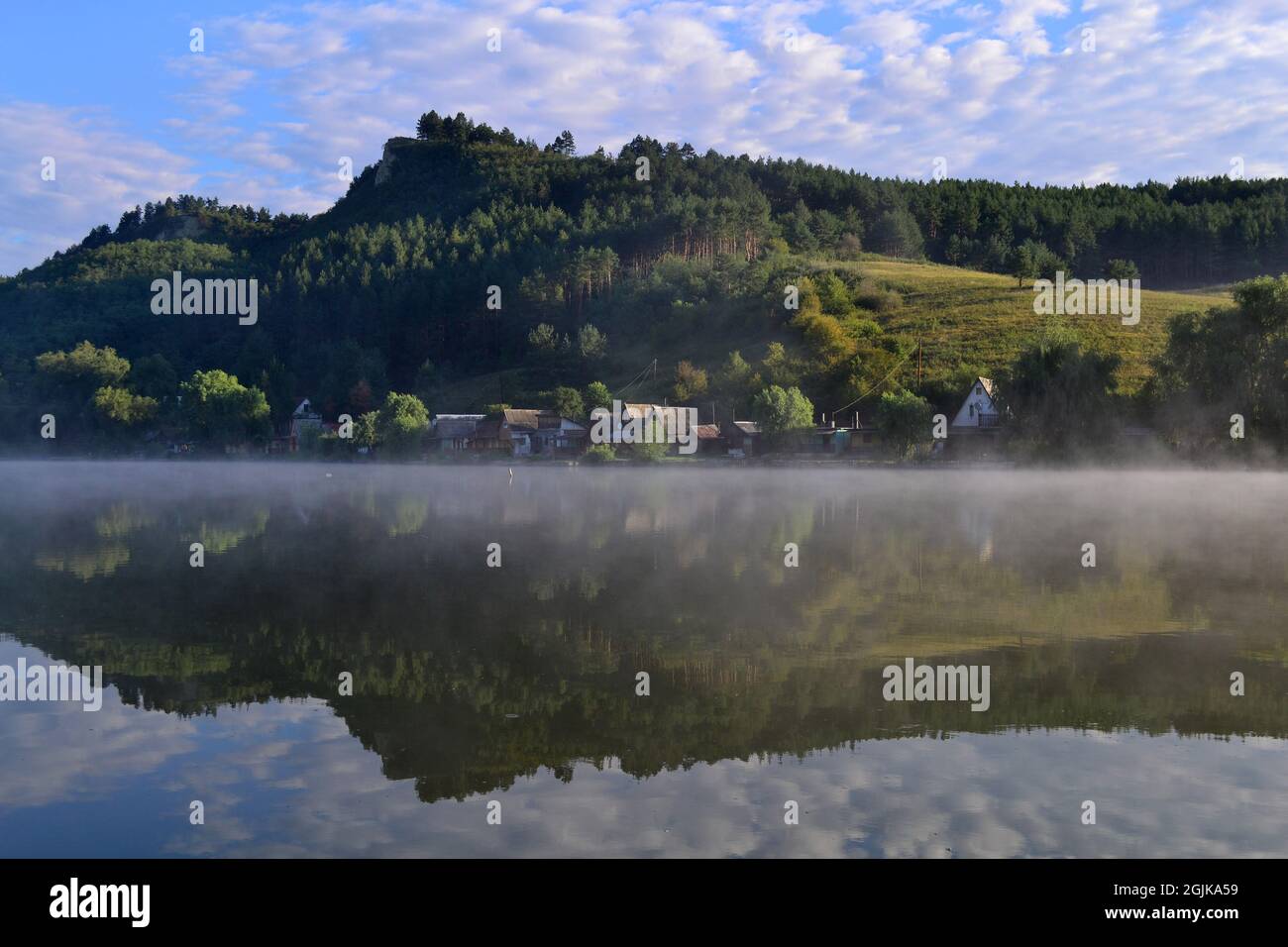 Maisons en bord de mer au bord du lac brumeux. Entre les collines à l'aube d'été. Arló, Hongrie. Banque D'Images