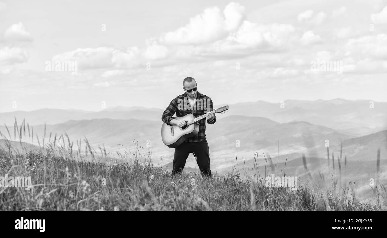 Randonneurs apprécient la nature. Le randonneur musicien trouve son  inspiration dans les montagnes. Restez calme et jouez de la guitare. Homme  randonneur avec guitare au sommet de la montagne. Musique pour l'âme