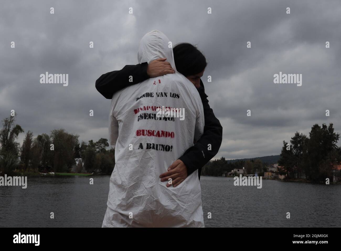 L'artiste mexicain porte un costume de sécurité biologique en protestation des disparus au Mexique, une femme l'embrasse en signe de soutien, sur le costume est écrit où les disparus vont, nous continuons à vous chercher bruno Banque D'Images