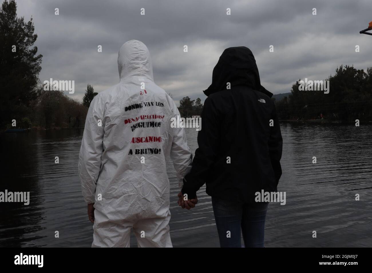 L'artiste mexicain porte un costume de sécurité biologique en protestation des disparus au Mexique, une femme l'embrasse en signe de soutien, sur le costume est écrit où les disparus vont, nous continuons à vous chercher bruno Banque D'Images