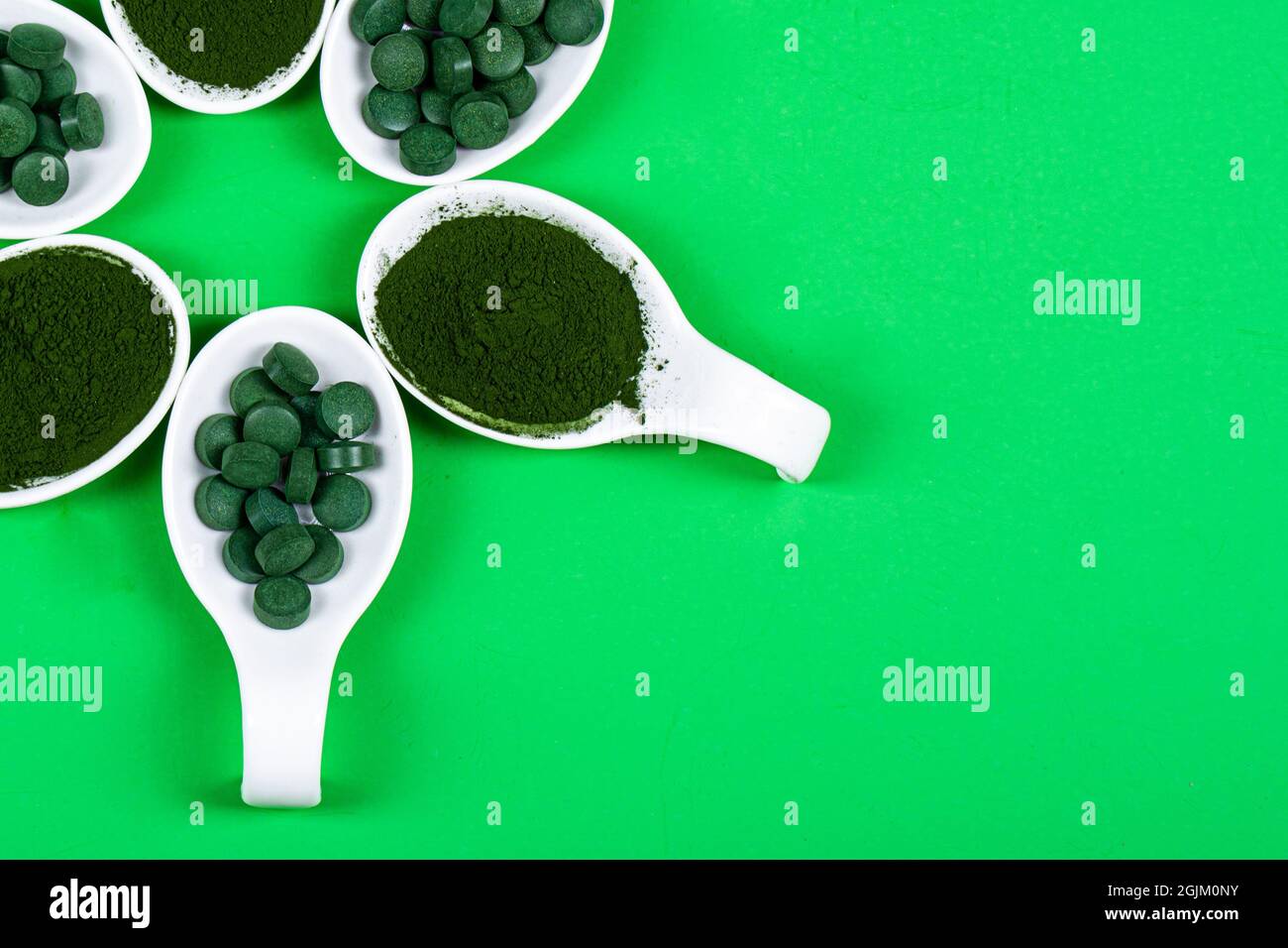Chlorella ou spiruline sous forme de comprimés et de poudre sur fond vert, gros plan. Banque D'Images