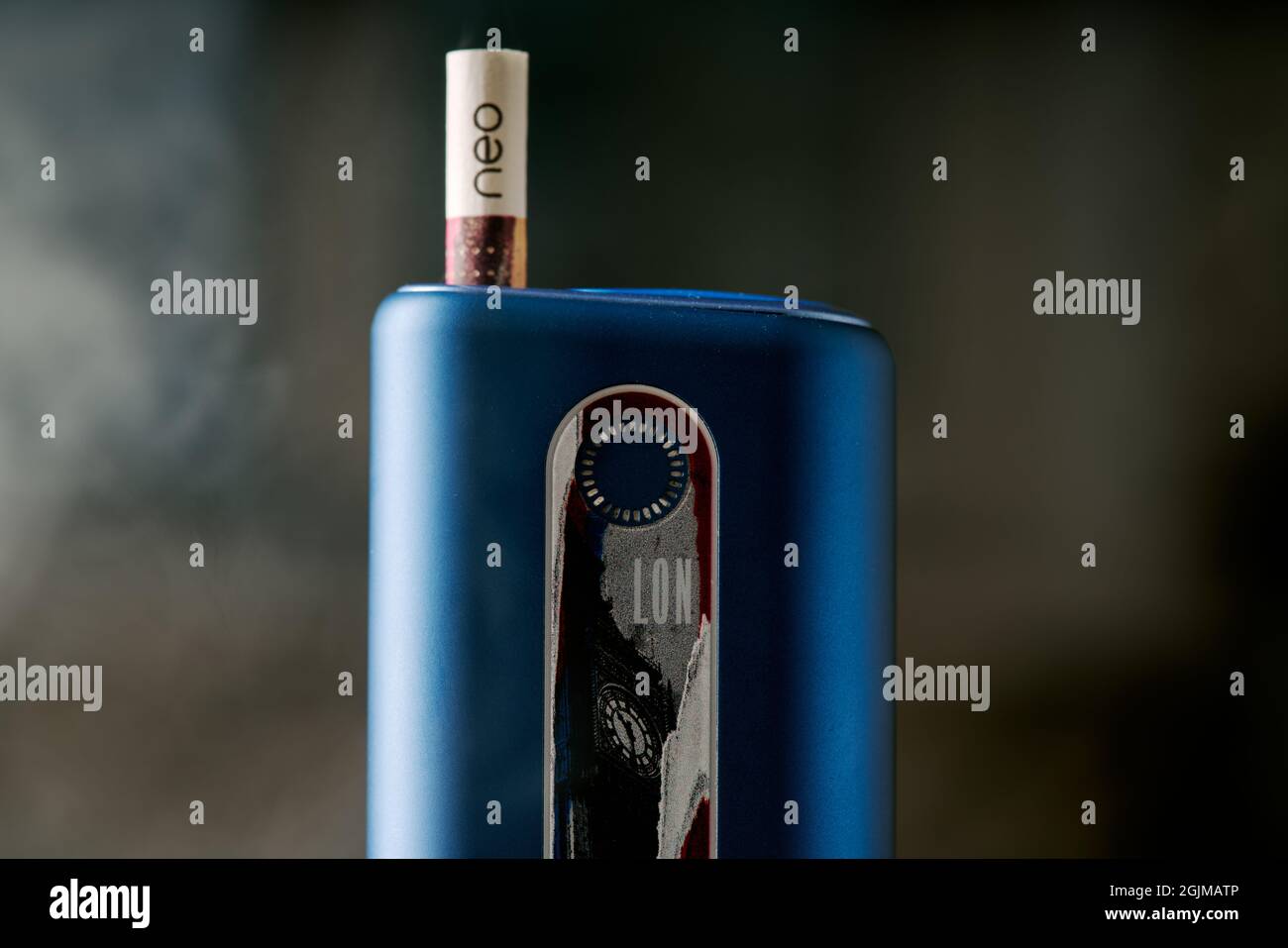 Cigarettes lectroniques GLO avec no-stick violet recouvert de fume sur  fond flou. Appareil London Glo bleu Photo Stock - Alamy