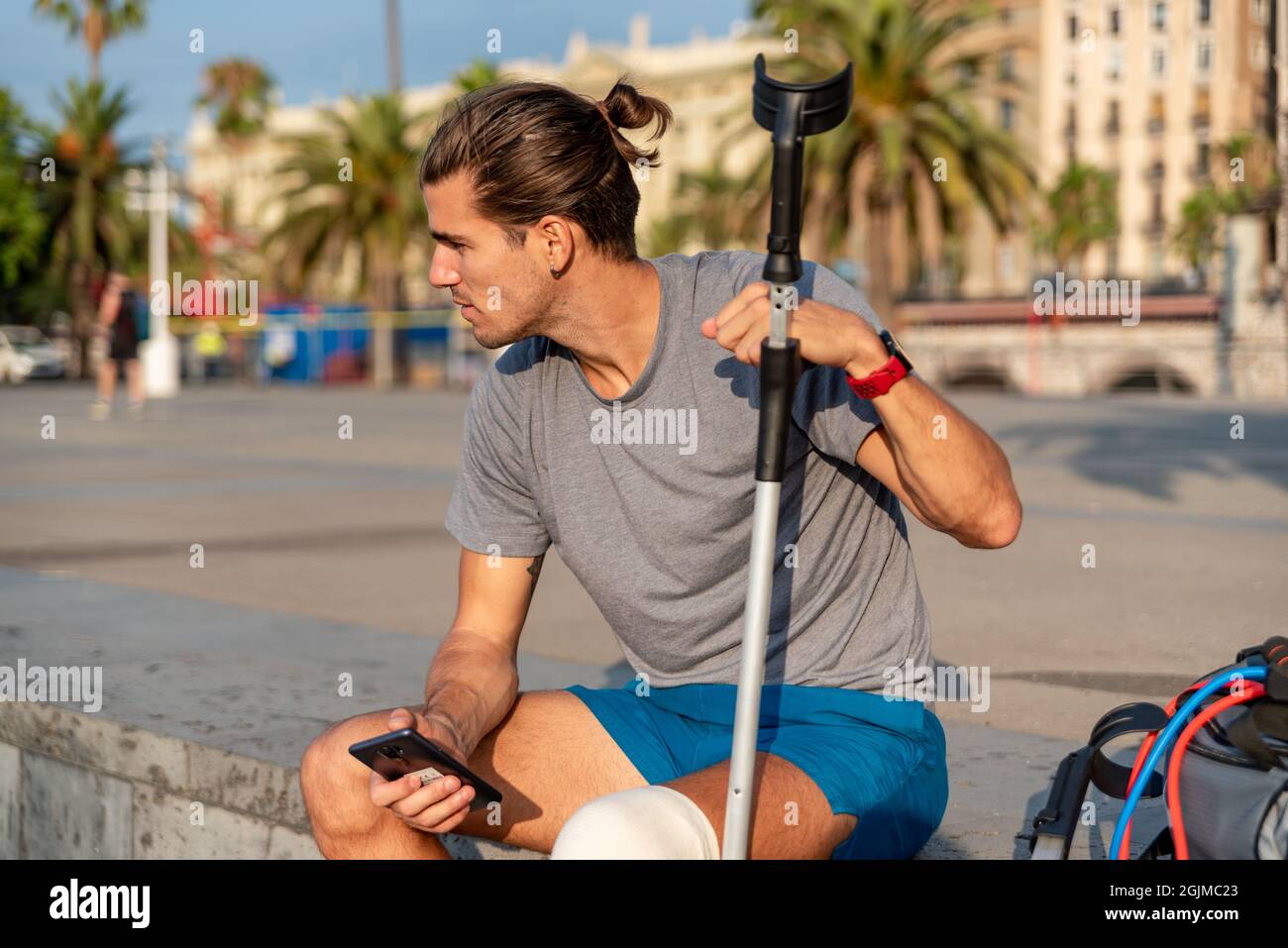 Jeune latin homme avec des béquilles en utilisant le téléphone portable après avoir fait de l'exercice Banque D'Images