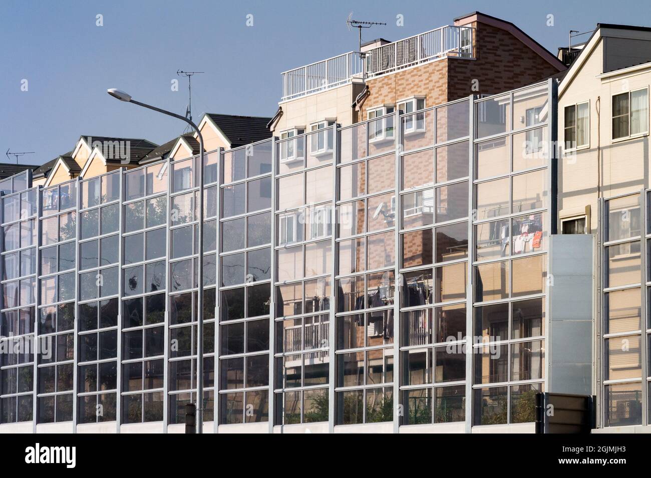 Maisons derrière un mur de verre insonorisant sur une route express à Kanagawa, Japon. Banque D'Images