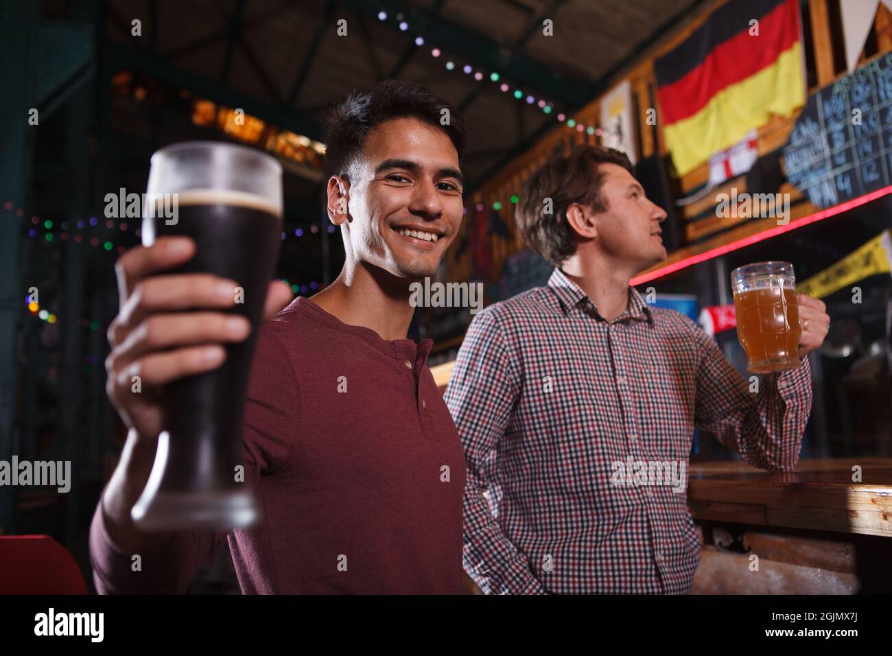 Joyeux homme beau en dégustant son verre de bière, se reposant au pub de bière avec un ami Banque D'Images