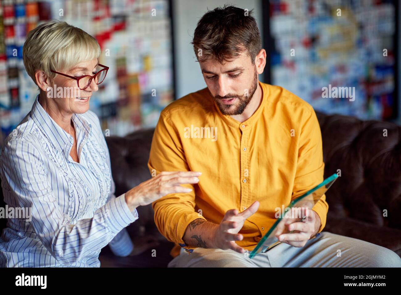 Une femme d'affaires plus âgée et un jeune collègue de sexe masculin dans une atmosphère de travail discutant de l'apparence d'un article. Affaires, bureau Banque D'Images