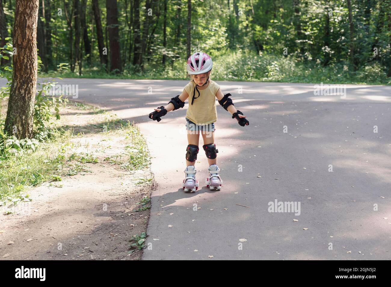 Enfant en vêtements de sport protecteurs. Petite fille apprenant à skate à  roulettes Photo Stock - Alamy