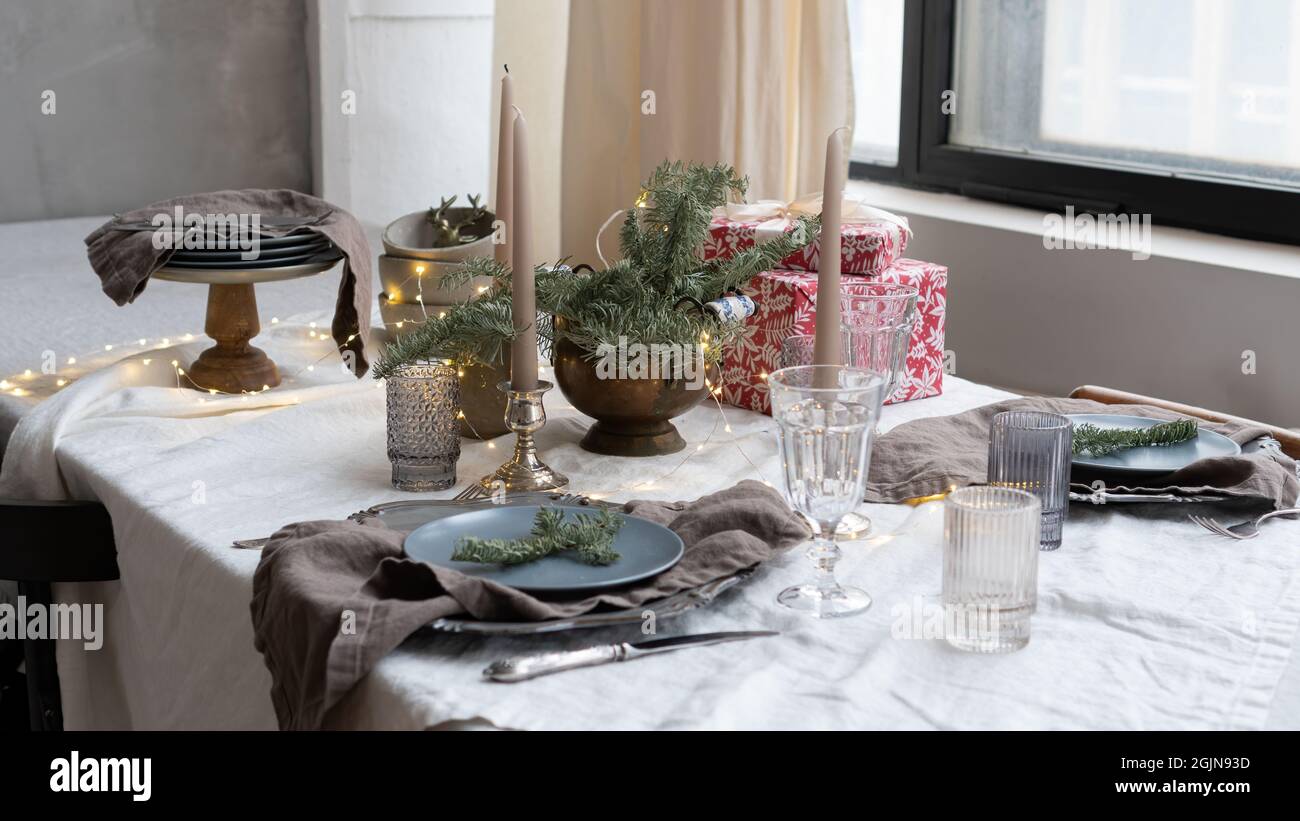 Décoration de Noël à l'intérieur du restaurant. Table pour le dîner de Noël avec brindilles, verres, bougies et boîtes-cadeaux. Style rustique Banque D'Images