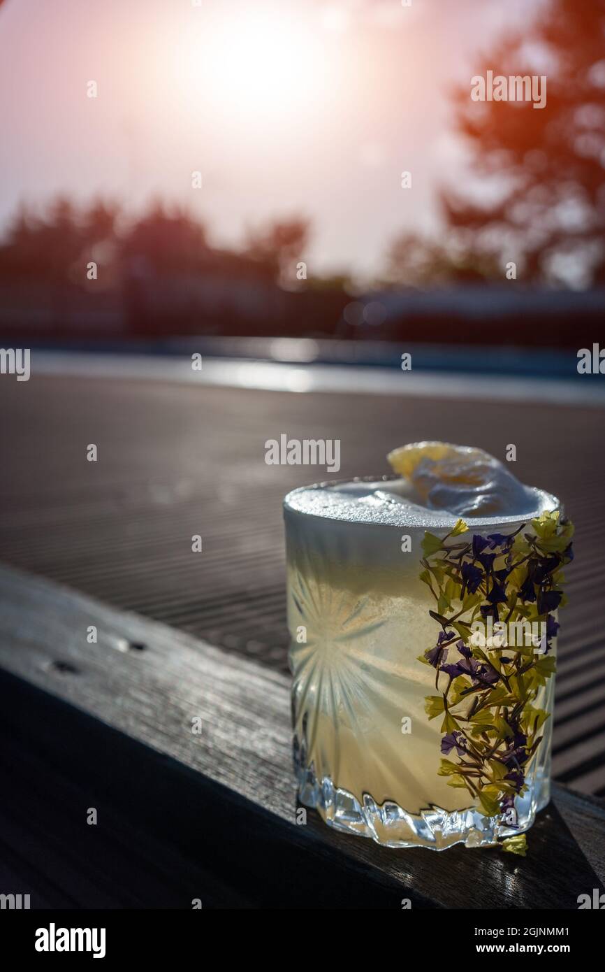 cocktail d'ananas à margarita rafraîchissant en verre garni de fleurs en plein air Banque D'Images