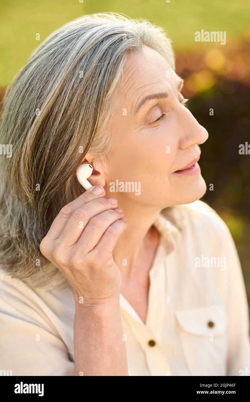 Femme tenant un écouteur près de l'oreille à l'extérieur Banque D'Images
