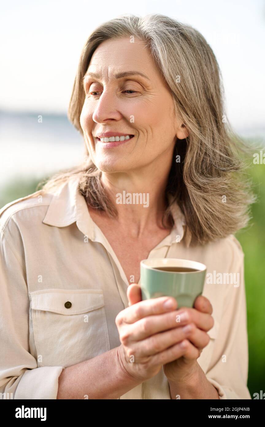 Femme pensive avec café dans la nature Banque D'Images