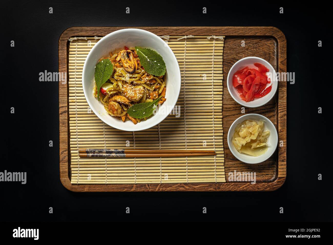 NOUILLES WOK avec fruits de mer et légumes. Moules, crevettes et calmars frits dans l'huile. Délicieux déjeuner asiatique dans un bol blanc sur fond noir. Remuer f Banque D'Images