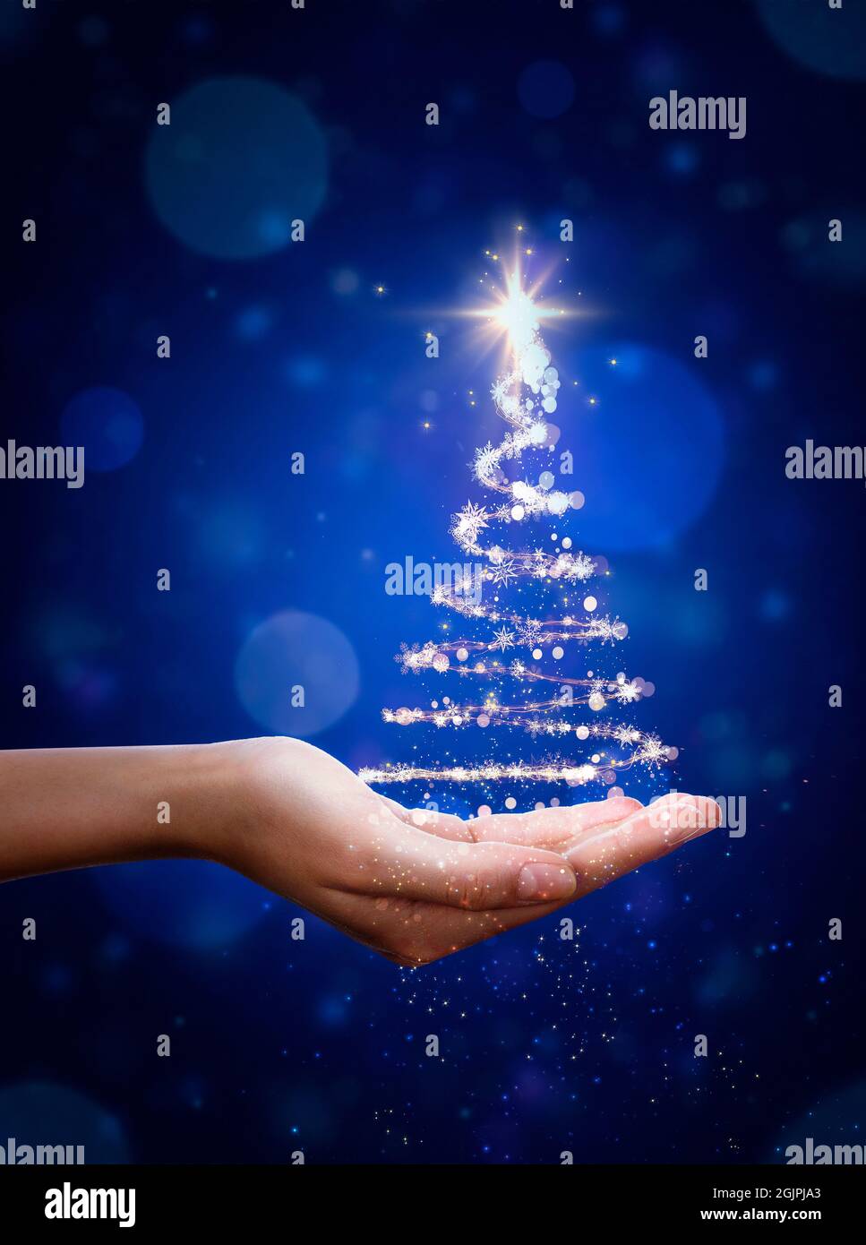 Arbre de Noël bleu à la main. Sapin de Noël, belles lumières, étoiles et flocons de neige Banque D'Images