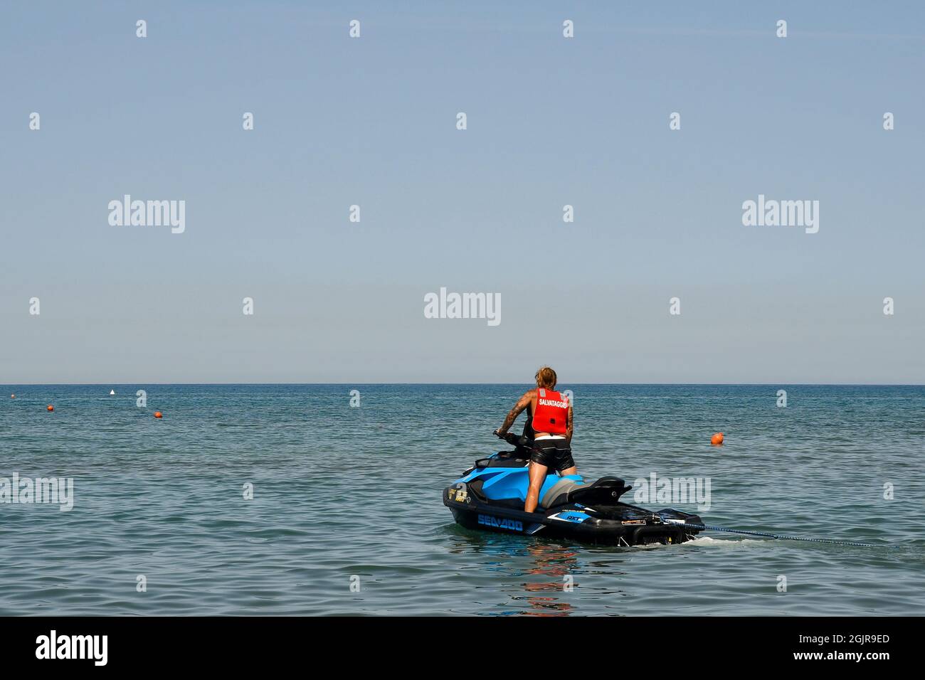 Un beau maître nageur à bord d'un jet ski sur la Méditerranée, un jour d'été avec une mer calme, Marina di Castagneto Carducci, Livourne, Toscane, Italie Banque D'Images