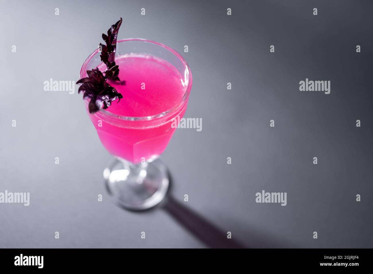 boisson alcoolisée de luxe rose avec basilic dans le verre sur fond gris Banque D'Images