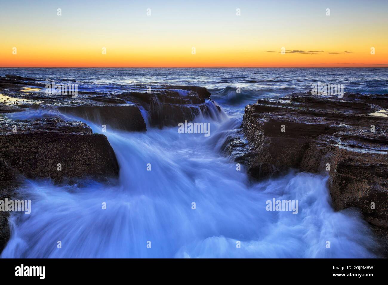 Tranchée robuste dans des rochers de grès sur les plages du nord de Sydney sur la côte de l'océan Pacifique au lever du soleil dans un paysage marin pittoresque. Banque D'Images