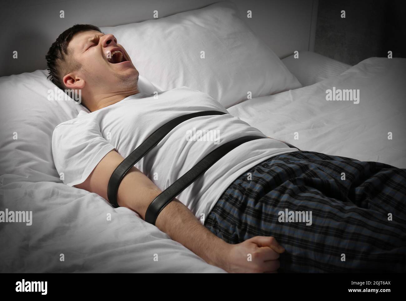 Jeune homme ligoté avec les courroies au lit Photo Stock - Alamy