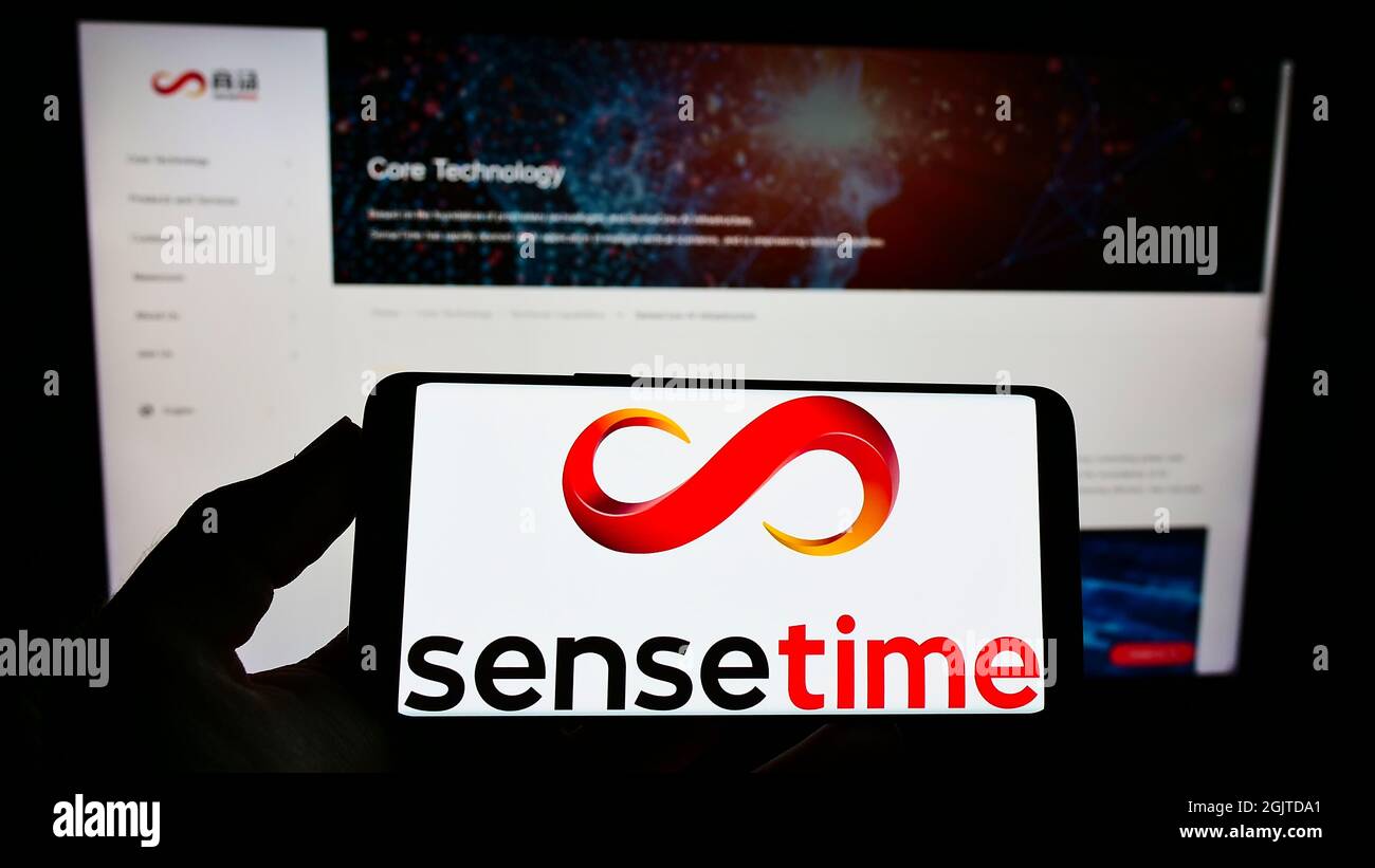 Personne tenant un téléphone portable avec le logo de la société chinoise d'intelligence artificielle SenseTime à l'écran en face de la page web. Mise au point sur l'affichage du téléphone. Banque D'Images