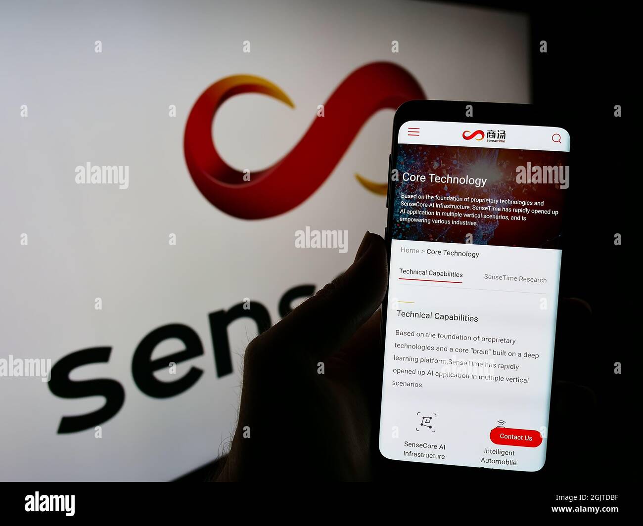 Personne tenant un téléphone portable avec la page web de la société chinoise d'intelligence artificielle SenseTime à l'écran devant le logo. Mise au point sur l'affichage du téléphone. Banque D'Images