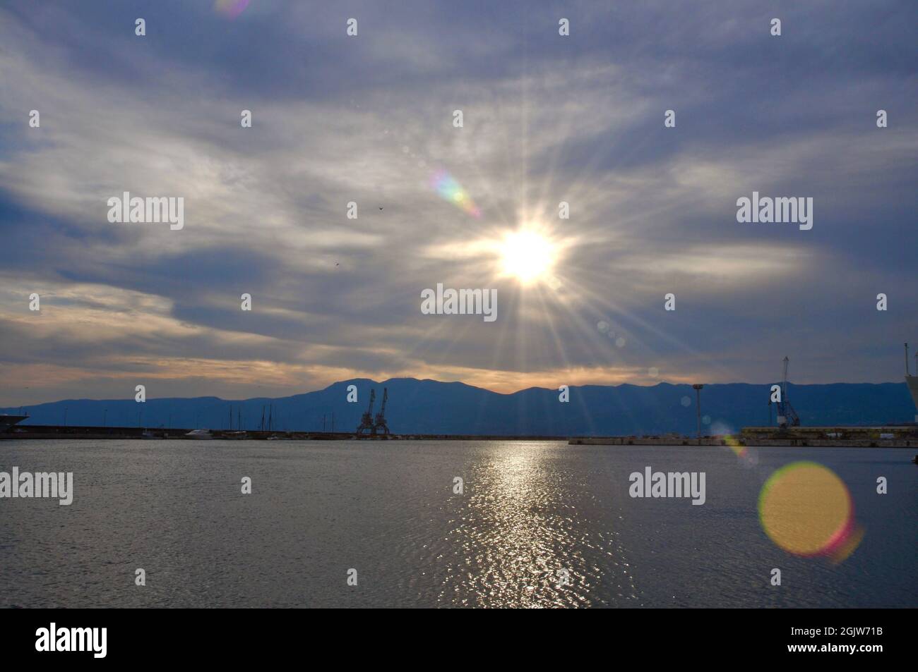 Grues industrielles sur la jetée de la ville de Rijeka, montagne en arrière-plan. Coucher de soleil sur la ville urbaine. Banque D'Images