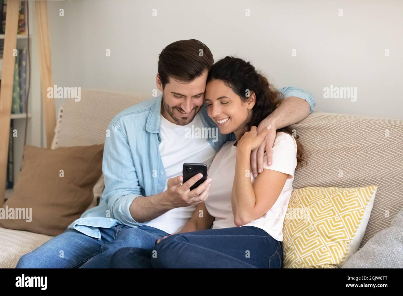 Couple se reposant sur un canapé à l'aide d'un smartphone, profitez de vos achats en ligne Banque D'Images