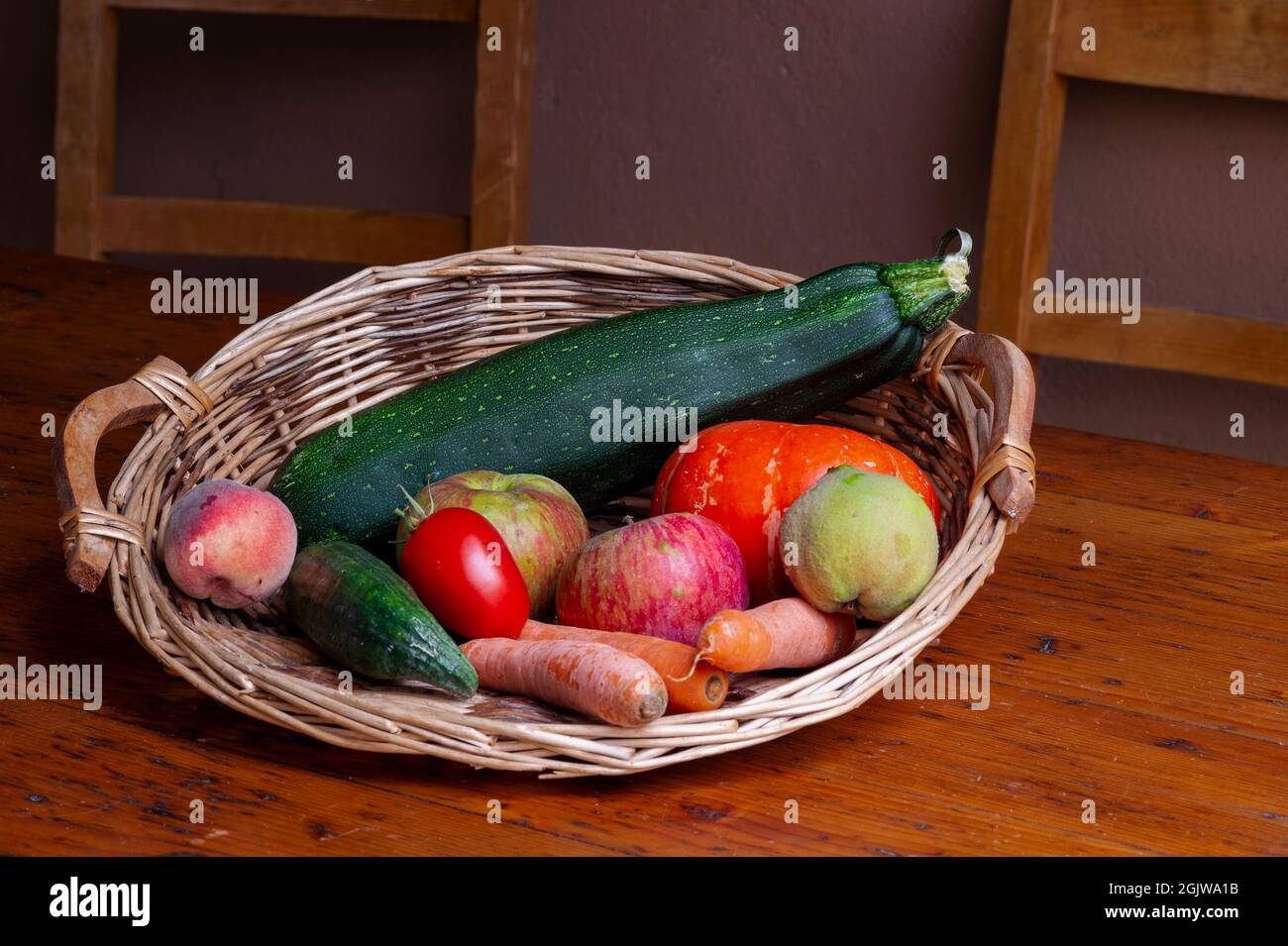 Fruits et légumes d'été, Alsace, France. Composition de produits de fin d'été présentés dans un panier en osier sur une table. Banque D'Images