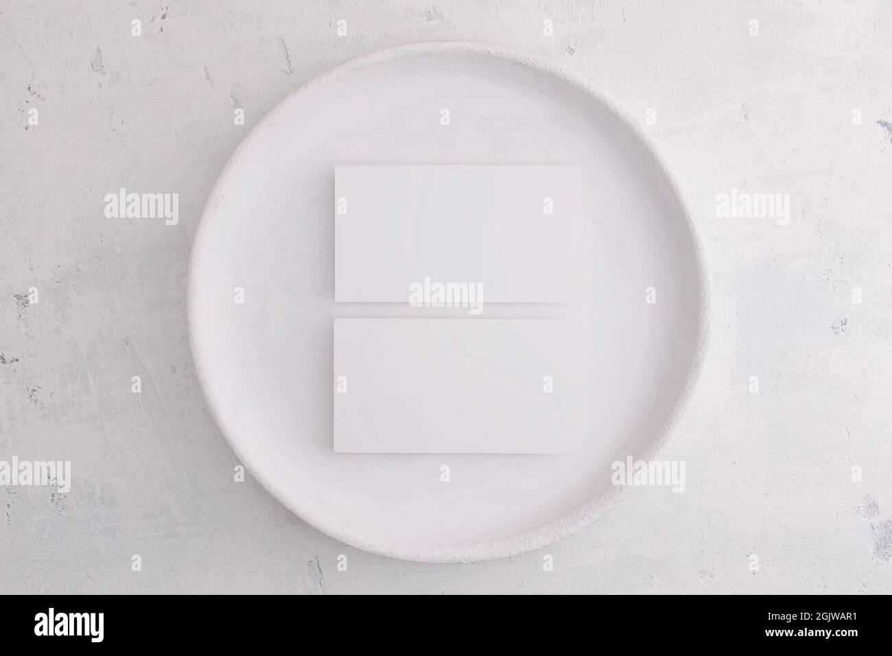 Les cartes de visite se masquent dans une assiette vintage blanche sur fond gris. Vue de dessus Banque D'Images