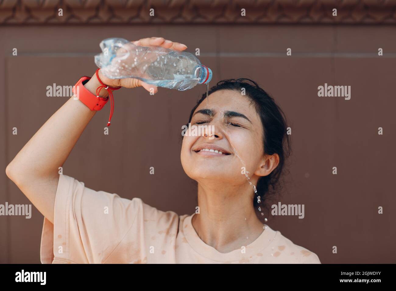 Femme stressée souffrant de coup de chaleur et de versement rafraîchissant avec de l'eau froide à l'extérieur. Concept de chaleur anormale par temps Banque D'Images