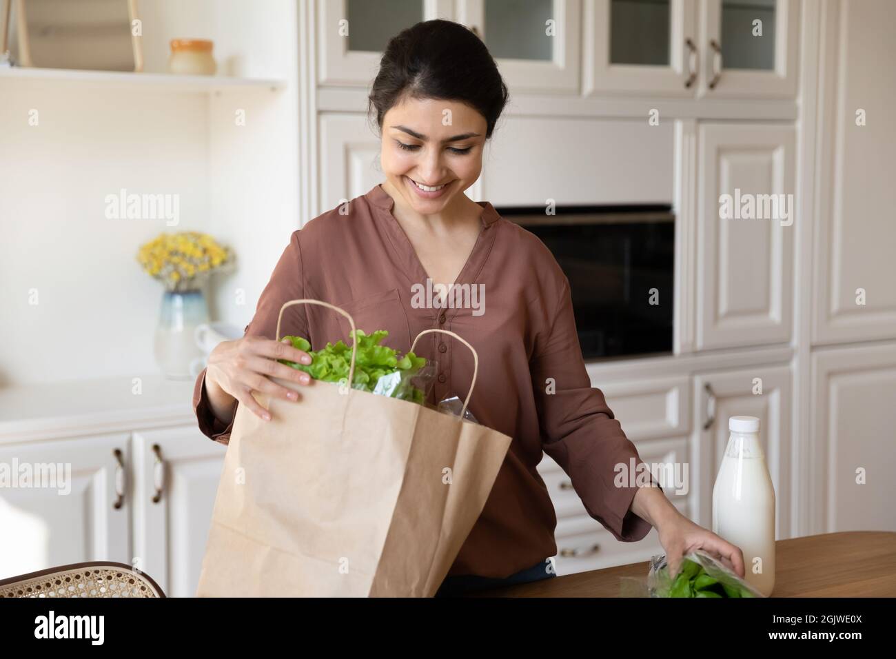 Une dame indienne heureuse a mis les produits alimentaires dans un sac en papier Banque D'Images