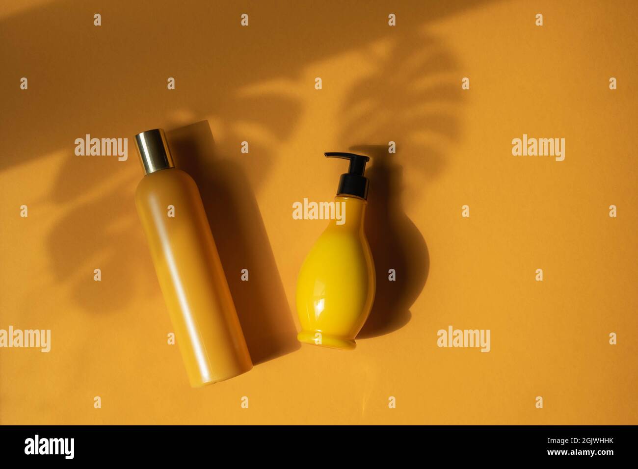 Maquette de bouteilles cosmétiques jaunes avec feuilles de monstère ombrées sur fond jaune. Une photo créative et minimaliste d'un produit cosmétique. Le concept o Banque D'Images