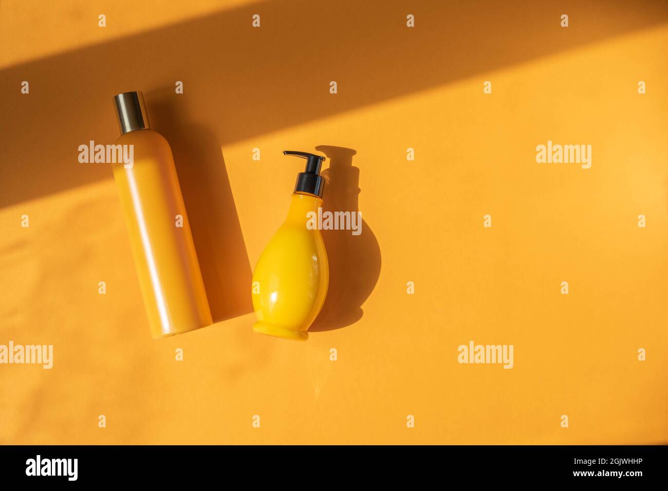 Maquette de bouteilles cosmétiques jaunes avec feuilles de monstère ombrées sur fond jaune. Une photo créative et minimaliste d'un produit cosmétique. Le concept o Banque D'Images