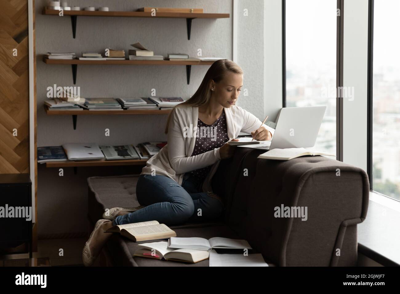 Une étudiante intelligente utilise un ordinateur portable pour étudier en ligne avec des livres Banque D'Images