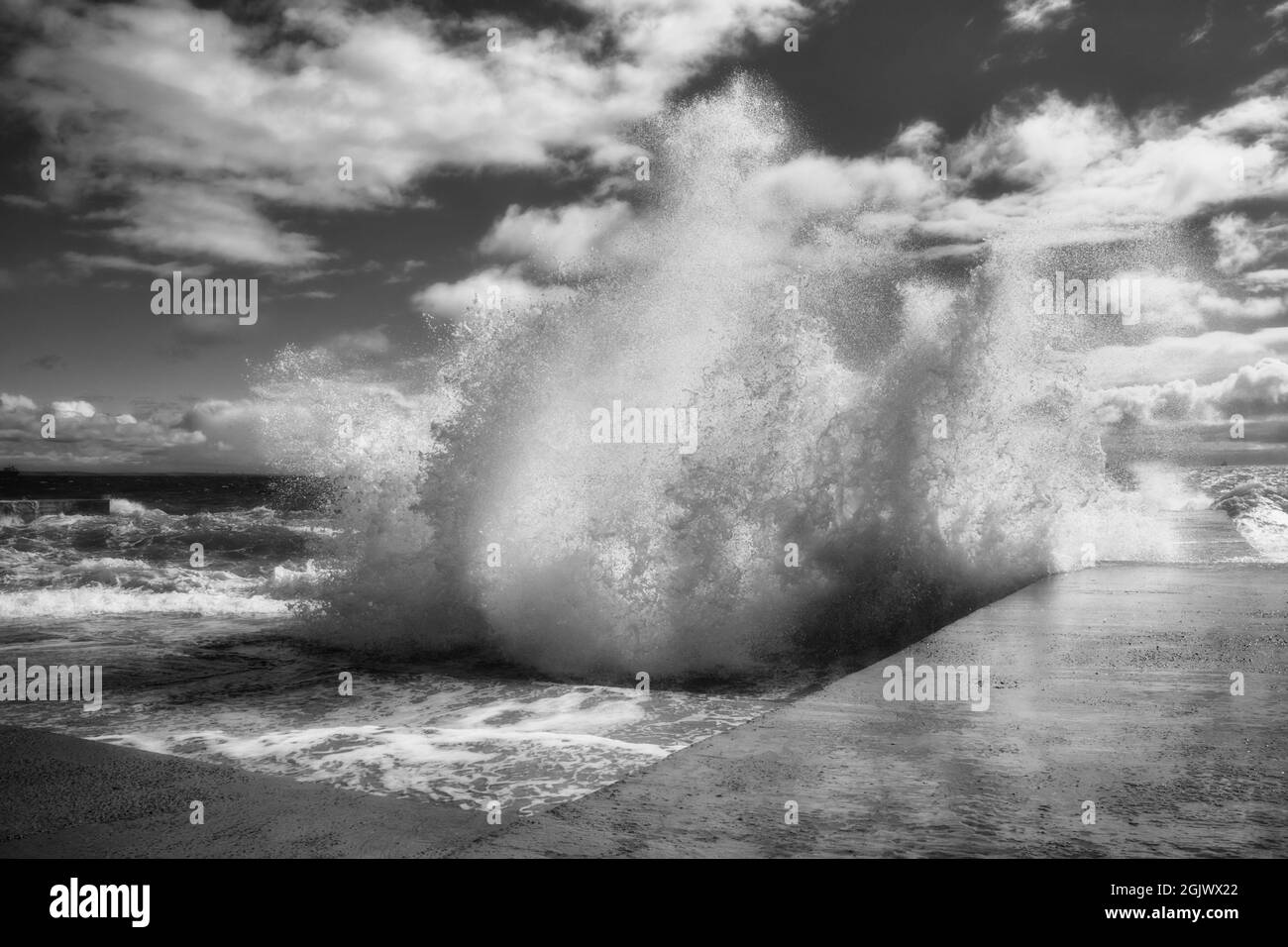 Vue spectaculaire sur les vagues de mer qui s'écrasant contre la jetée en béton. Puissance de la nature. Noir et blanc Banque D'Images