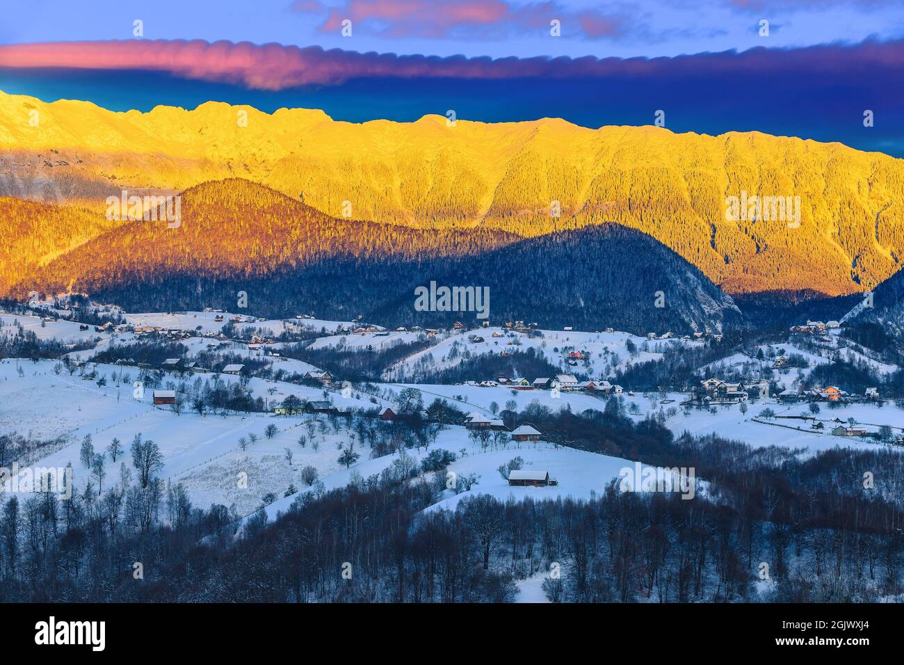 Paysage magique de l'aube d'hiver avec des montagnes enneigées spéculaires. Lever de soleil à couper le souffle et crête de montagne enneigée en arrière-plan, montagnes Piatra CRAiului, Banque D'Images