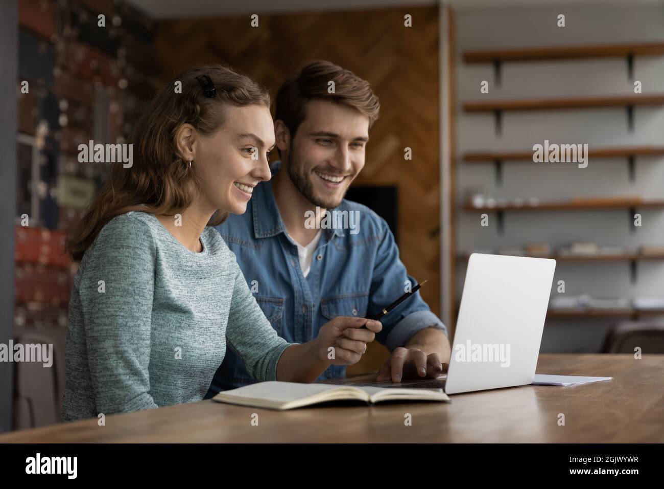 Des collègues heureux et variés travaillent sur un ordinateur portable sur leur lieu de travail Banque D'Images