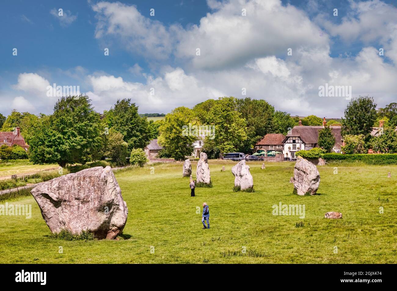 8 juin 2019 : Avebury, Wiltshire, Royaume-Uni - le cercle de pierres d'Avebury, et les touristes marchant parmi les mégalithes, avec le village d'Avebury dans le fond. Banque D'Images