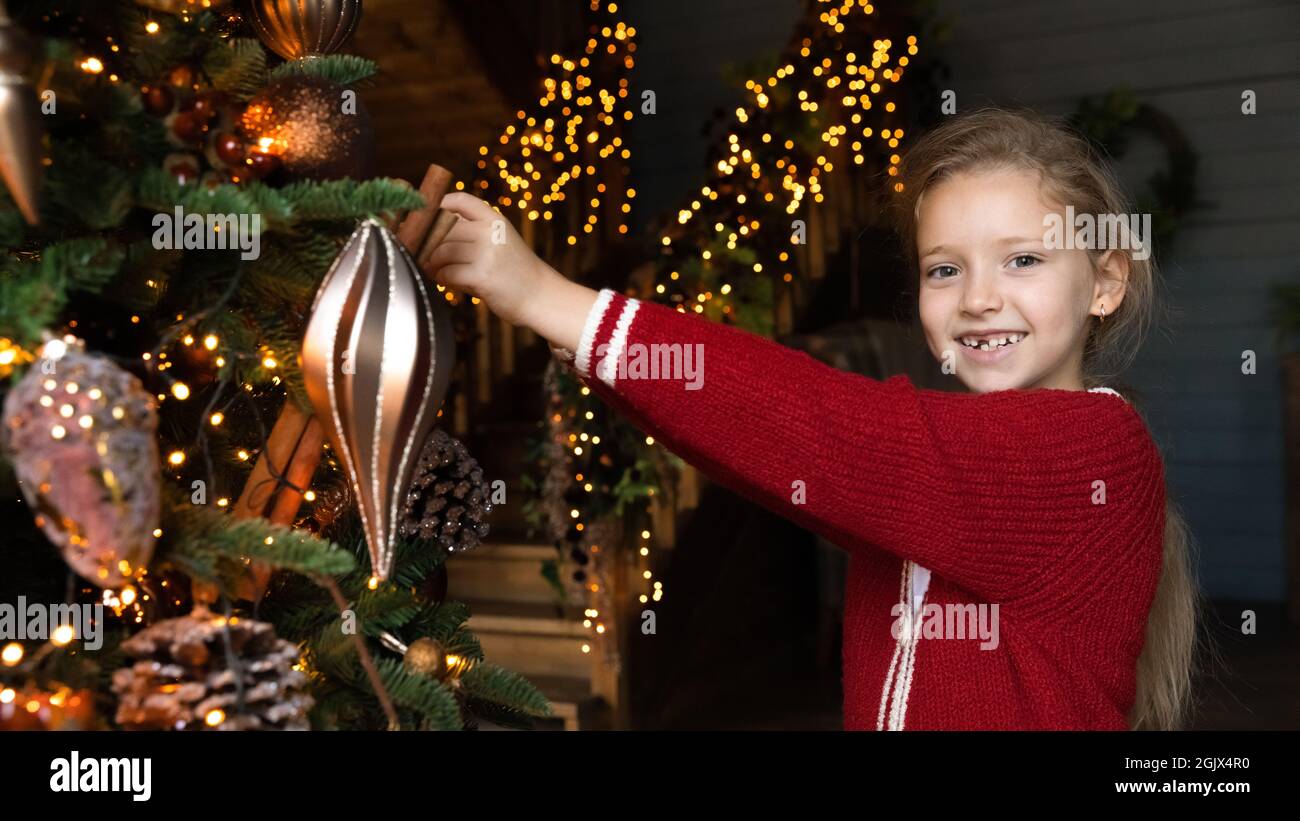 Portrait de sourire adorable petite fille de gamin décorant l'arbre de Noël. Banque D'Images