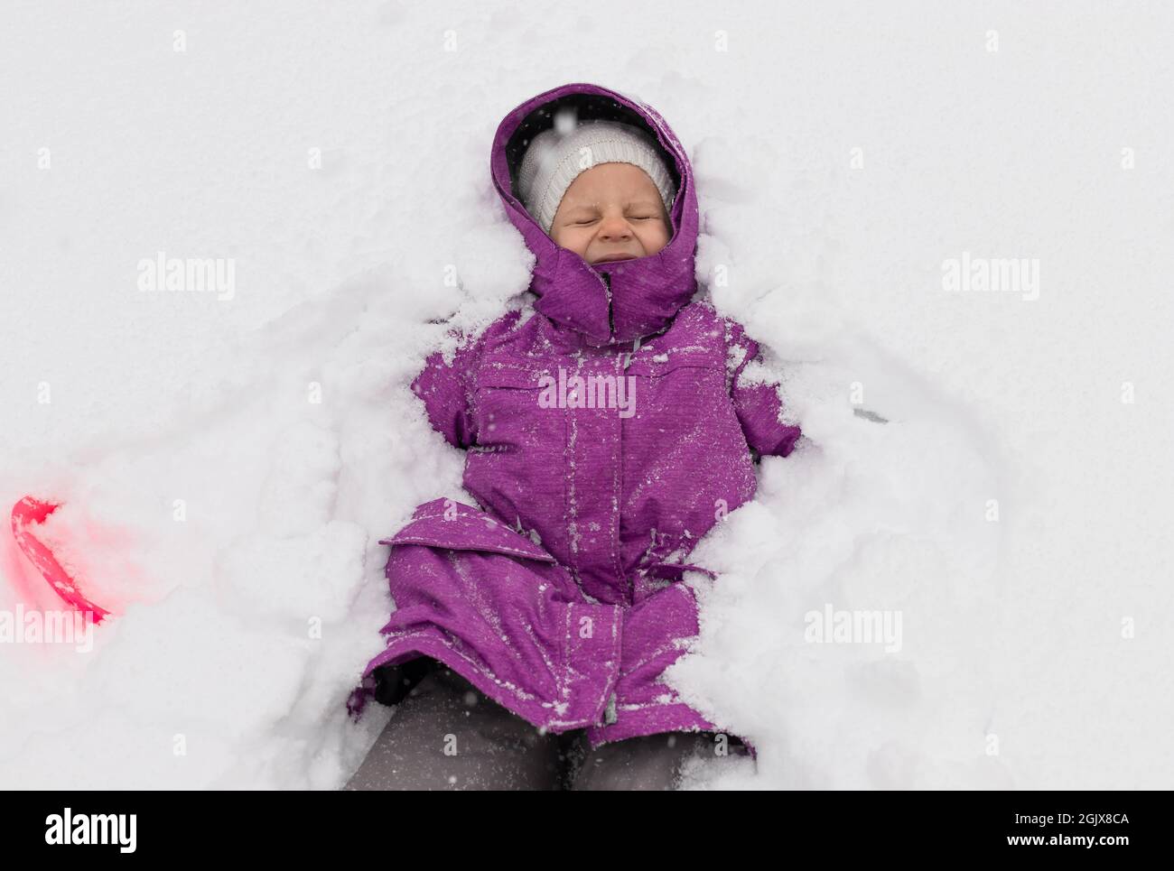 bonne fille d'avant-chooler jouant sur la neige en vacances d'hiver Banque D'Images