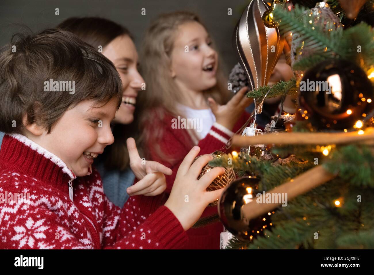 Joyeux petits enfants décorant arbre de Noël avec maman. Banque D'Images