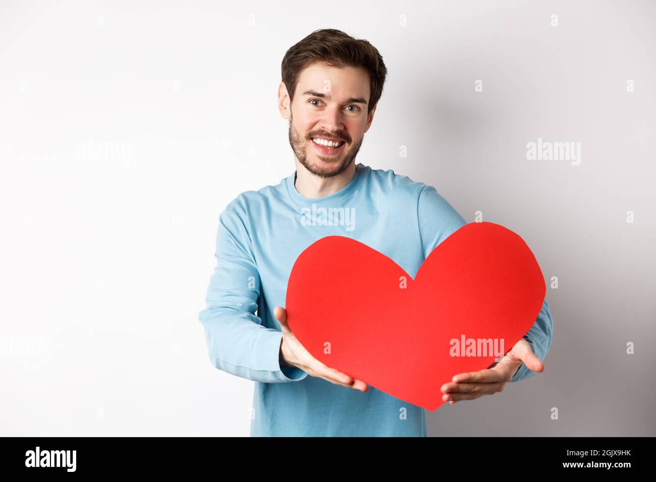 Joyeux gay homme donnant un grand coeur rouge à son amant le jour de la Saint  Valentin, concept de célébration romantique de la date et de l'amour,  debout sur fond blanc Photo