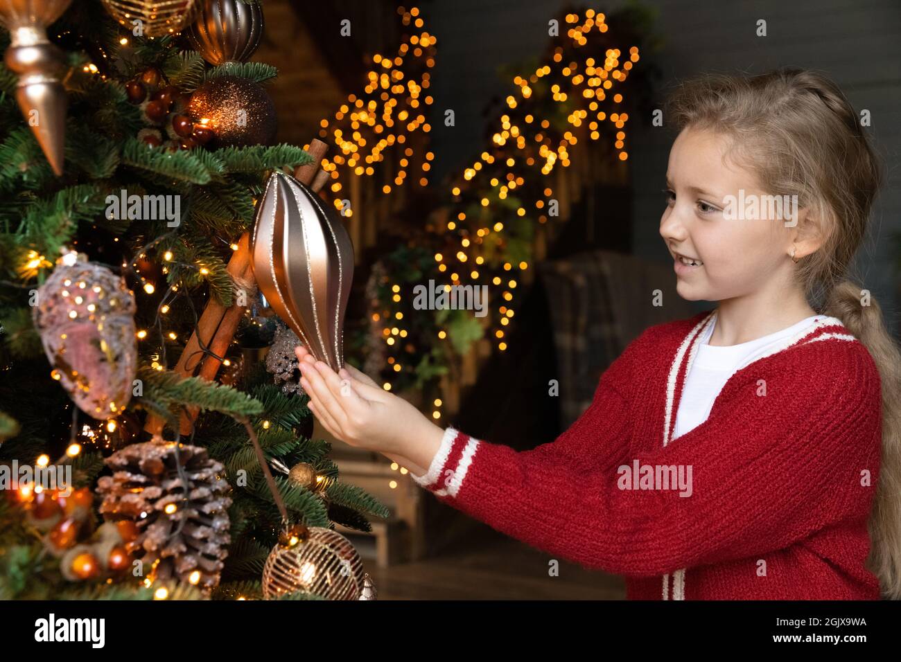 Joyeux petit mignon joli enfant fille décorant arbre de Noël. Banque D'Images