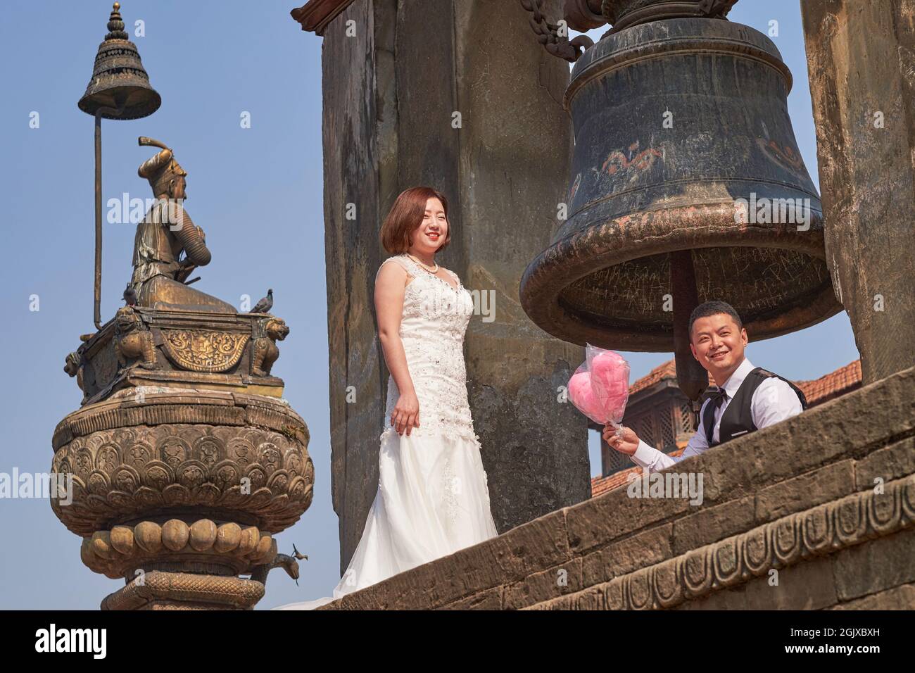 Un couple de mariage d'extrême-Orient posant pour des photos à la cloche de Taleju et à côté d'une statue du roi Bhupatindra Malla; place Durbar, Bhaktapur, Népal Banque D'Images