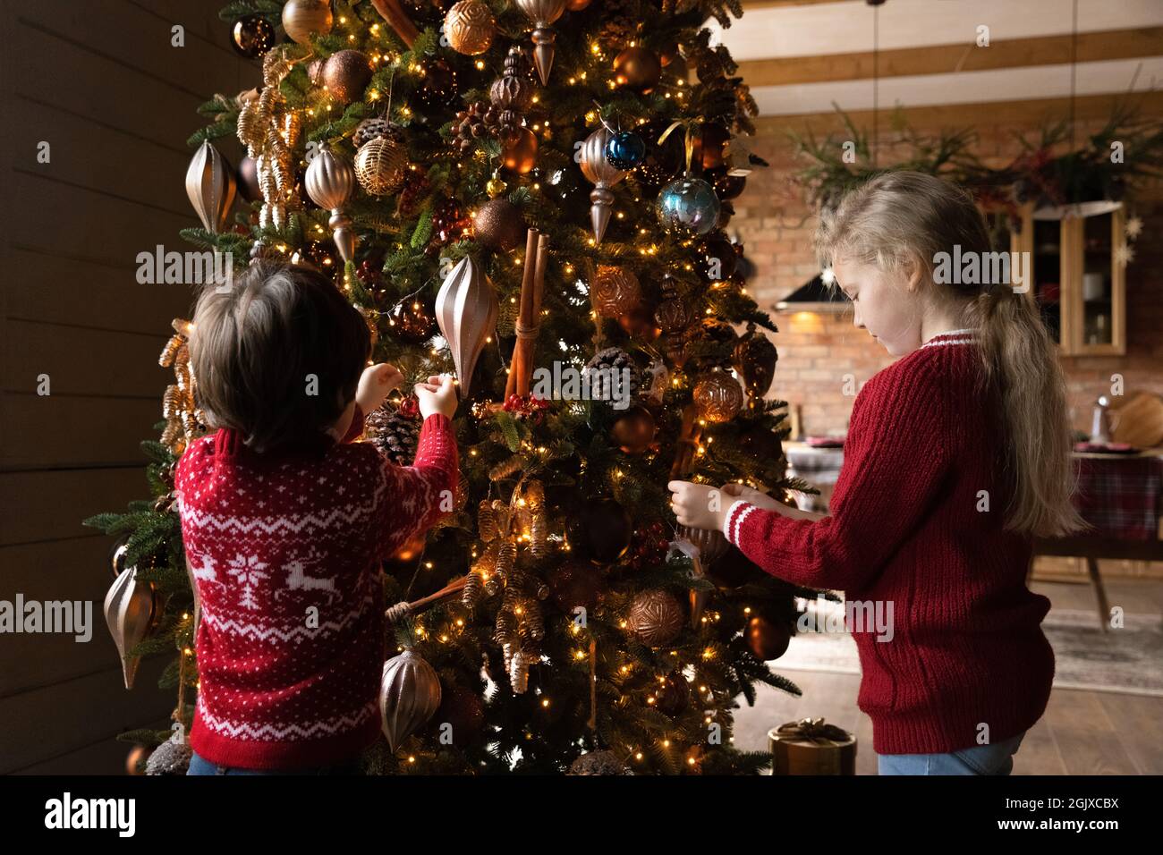 Joyeux petits enfants frères et sœurs concevant un arbre de Noël à l'aide de boules décoratives. Banque D'Images